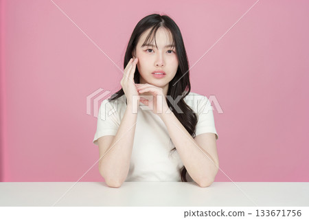 Beauty and Self-Care. Young woman posing with hands on her face against a pink background. 133671756