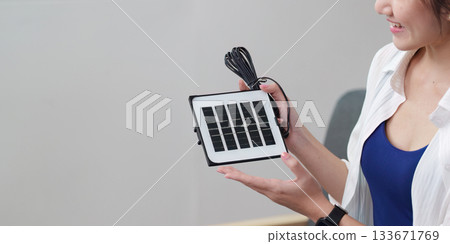 Solar energy. Woman holding a solar panel for sustainable power. 133671769