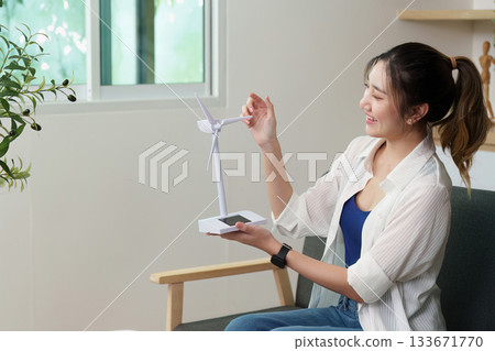 Renewable energy. Woman showcasing a miniature wind turbine model. Renewable energy. Woman showcasing a miniature wind turbine model. 133671770