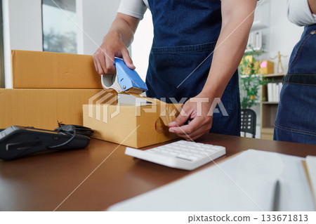 Efficient packaging. Worker sealing boxes for shipping in office. Efficient packaging. Worker sealing boxes for shipping in office. 133671813
