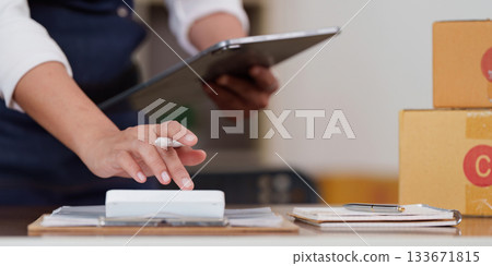 Efficiency. Individual managing tasks with tablet and calculator in a modern workspace. Efficiency. Individual managing tasks with tablet and calculator in a modern workspace. 133671815