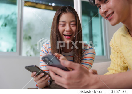 Digital Connection. Young friends engaging with smartphones in a cozy indoor setting. Digital Connection. Young friends engaging with smartphones in a cozy indoor setting. 133671883