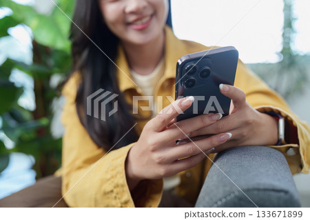 Lifestyle. Young woman enjoying smartphone in cozy indoor setting. Lifestyle. Young woman enjoying smartphone in cozy indoor setting. 133671899