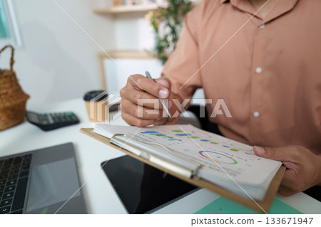 Financial Review. Young professional analyzing charts and graphs in a modern workspace. Financial Review. Young professional analyzing charts and graphs in a modern workspace. 133671947