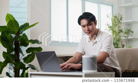 Smart Technology. A man working on laptop with smart speaker at home. Smart Technology. A man working on laptop with smart speaker at home. 133671998