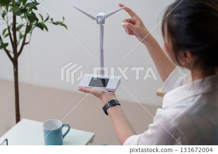 Renewable Energy. Woman showcasing a wind turbine model for sustainable energy. Renewable Energy. Woman showcasing a wind turbine model for sustainable energy. 133672004