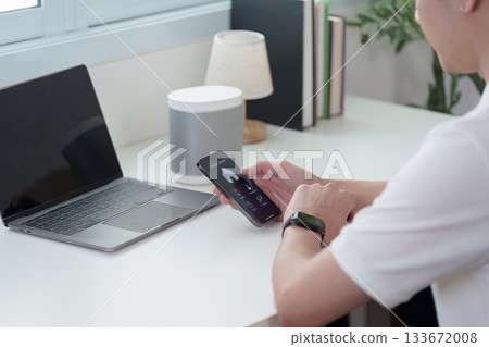 Smart Technology. A man using smartphone with smart speaker on desk. Smart Technology. A man using smartphone with smart speaker on desk. 133672008