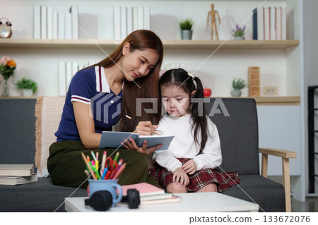 Creative Learning Moment. A mother and daughter engage in writing activities at home. Creative Learning Moment. A mother and daughter engage in writing activities at home. 133672076
