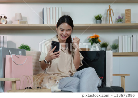 Joyful Shopping. Woman celebrating successful online purchase with smartphone. 133672096