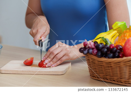 Food Wellness: Woman Cutting Tomato for Nutritious Meal Prep 133672145