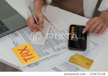 Tax assessment. Individual calculating tax liabilities with documents. Tax assessment. Individual calculating tax liabilities with documents. 133672149