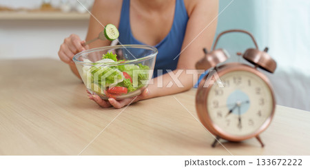 Food Wellness: Woman preparing fresh salad with clock in view Food Wellness: Woman preparing fresh salad with clock in view 133672222
