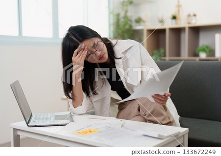 Tax stress. Young woman feeling overwhelmed by financial paperwork. 133672249