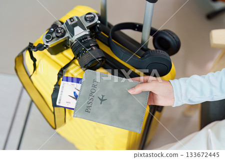 Travel Planning. Preparing for a trip with a suitcase, camera, and passport in hand. Travel Planning. Preparing for a trip with a suitcase, camera, and passport in hand. 133672445