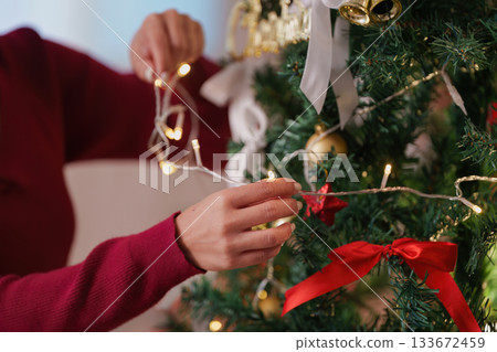 SSTK Christmas: Woman stringing lights on the Christmas tree 133672459