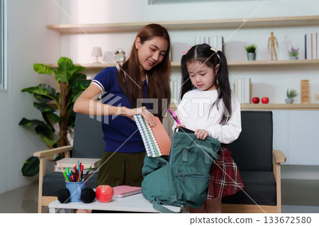 Mother Assisting Daughter with School Backpack Organization Mother Assisting Daughter with School Backpack Organization 133672580