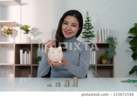 Savings Strategy. Woman smiling while holding piggy bank and planning finances. Savings Strategy. Woman smiling while holding piggy bank and planning finances. 133672588