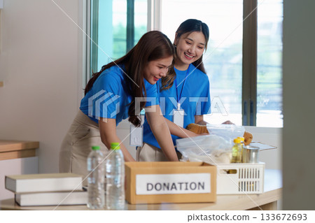 Volunteering for Food Donation. Two young women organizing donations in a community center. 133672693