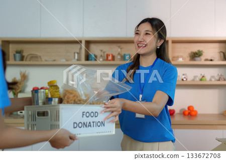 Food Donation Initiative. Volunteer handing over food donation box with joy. 133672708