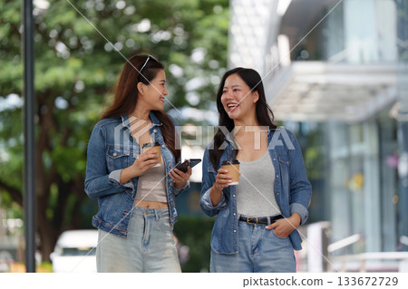 Friendship and Connection. Two young women enjoying coffee and conversation outdoors. 133672729