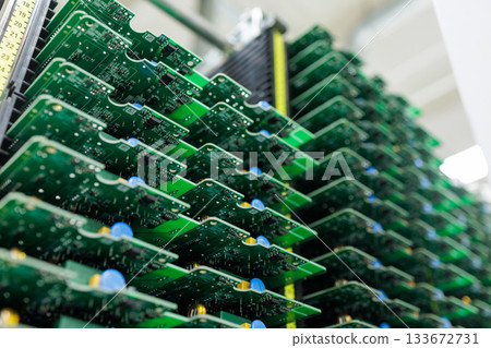 Rows of assembled green circuit boards stacked in rack inside modern automated electronics manufacturing plant 133672731
