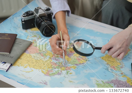Travel Planning. Two friends exploring destinations on a map with camera and passport. Travel Planning. Two friends exploring destinations on a map with camera and passport. 133672740