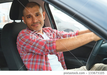 Happy hispanic man driving car smiling at camera 133673105