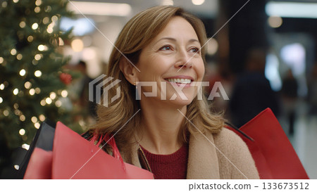 Happy Woman Carrying Christmas Gifts with Joyful Smile Shopping in Holiday Season Festive Mall Atmosphere 133673512