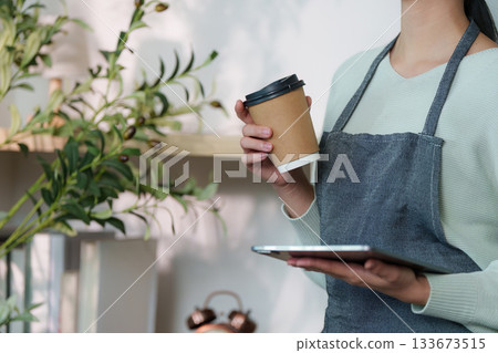 Barista with Coffee and Tablet in Cozy Cafe Environment Barista with Coffee and Tablet in Cozy Cafe Environment 133673515