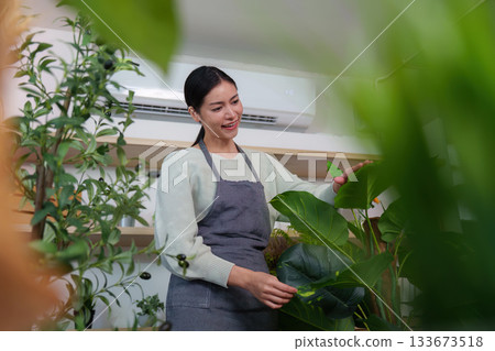 Plant Enthusiast. Woman interacting with greenery while taking notes in a sustainable shop. Plant Enthusiast. Woman interacting with greenery while taking notes in a sustainable shop. 133673518