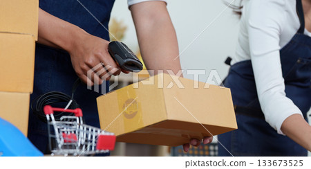 Efficient Logistics. Man scanning a package with a barcode scanner in a modern workspace. 133673525