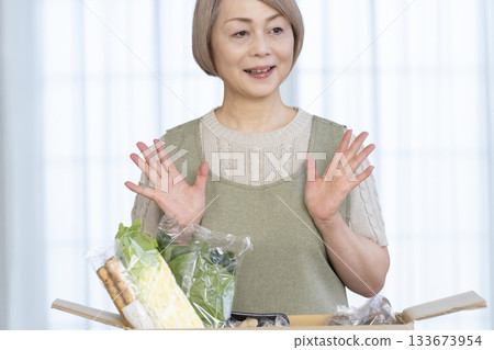 一位老婦人欣喜地看著農場直接把蔬菜送到她家客廳。 一位老婦人欣喜地看著農場直接把蔬菜送到她家客廳。 133673954