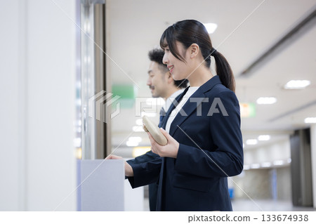 A business woman on a business trip buying a ticket at a ticket machine at a station or airport 133674938