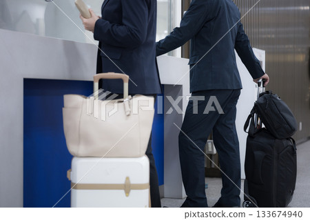 Business woman on a business trip buying a ticket from a ticket machine at a station or airport, checking in suitcases and luggage at a counter, faceless Business woman on a business trip buying a ticket from a ticket machine at a station or airport, checking in suitcases and luggage at a counter, faceless 133674940