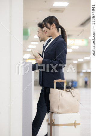 一位出差的職業婦女在車站或機場的自動售票機上購買車票。 一位出差的職業婦女在車站或機場的自動售票機上購買車票。 133674941