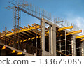 Monolithic Box under Construction with Yellow Volumetric I-Beams. Concrete Wall Frame Building with Formwork Prints and Rebar releases on Construction Site. Architectural origin Structure Sunny day. 133675085