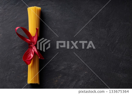 Raw Dry Spaghetti Tied in Bundle on Dark Surface Italian Cuisine 133675364