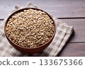 Uncooked Whole Oats in Beige Bowl on Wooden Background Close Up Uncooked Whole Oats in Beige Bowl on Wooden Background Close Up 133675366