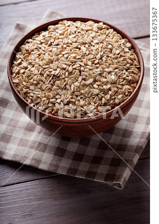 Uncooked Whole Oats in Beige Bowl on Wooden Background Close Up 133675367