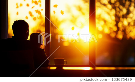 Silhouette of a parent and child watching sunset through window. 133675489
