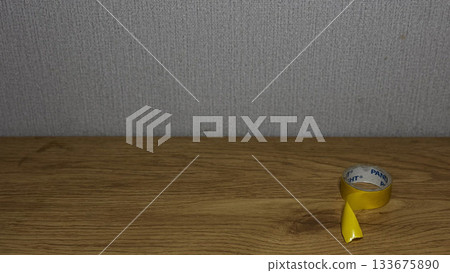 Close-up of yellow tape on a wooden surface. 133675890