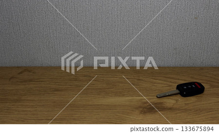Close-up of a car key resting on a wooden surface. 133675894