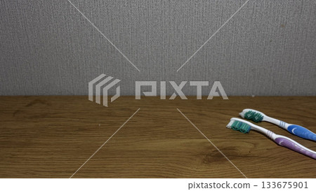 Bright toothbrushes on a wooden table, ideal for dental hygiene themes. Bright toothbrushes on a wooden table, ideal for dental hygiene themes. 133675901