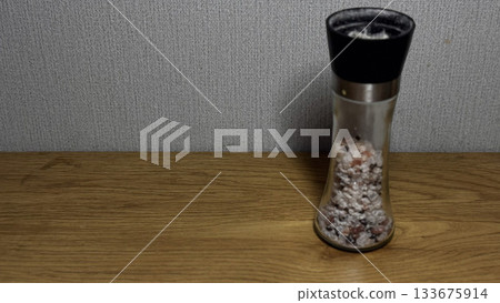 Stylish salt grinder with pink Himalayan salt on wood. Stylish salt grinder with pink Himalayan salt on wood. 133675914