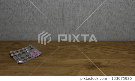 Close-up of a blister pack with pink pills on wooden surface. 133675920