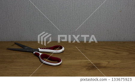 Close-up of scissors resting on a wooden surface. Close-up of scissors resting on a wooden surface. 133675923