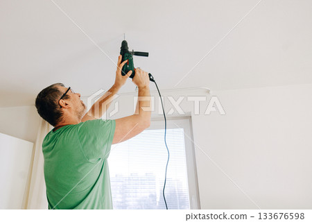 Man using electric drill to Man using electric drill to 133676598
