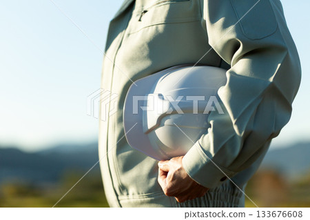 A middle-aged male businessman wearing work clothes and holding a helmet A middle-aged male businessman wearing work clothes and holding a helmet 133676608