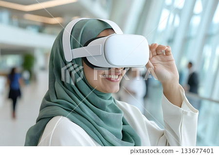 Woman in Hijab Engaging with Virtual Reality Technology in Modern Indoor Space 133677401