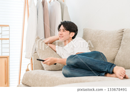 Young Asian man lying on the sofa watching TV 133678491